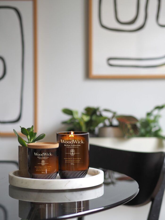 Mehrere WoodWick ReNew Collection Kerzen auf Tischen im Wohnraum