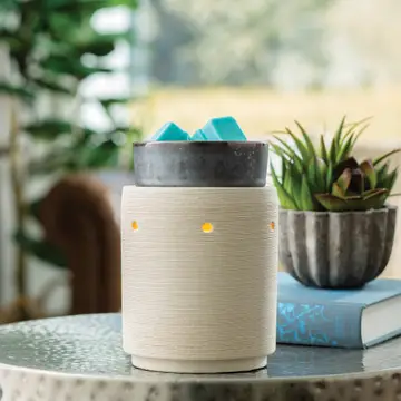 Elektrische Duftlampe mit türkisfarbenen Würfeln auf einem Tisch neben Pflanzen
