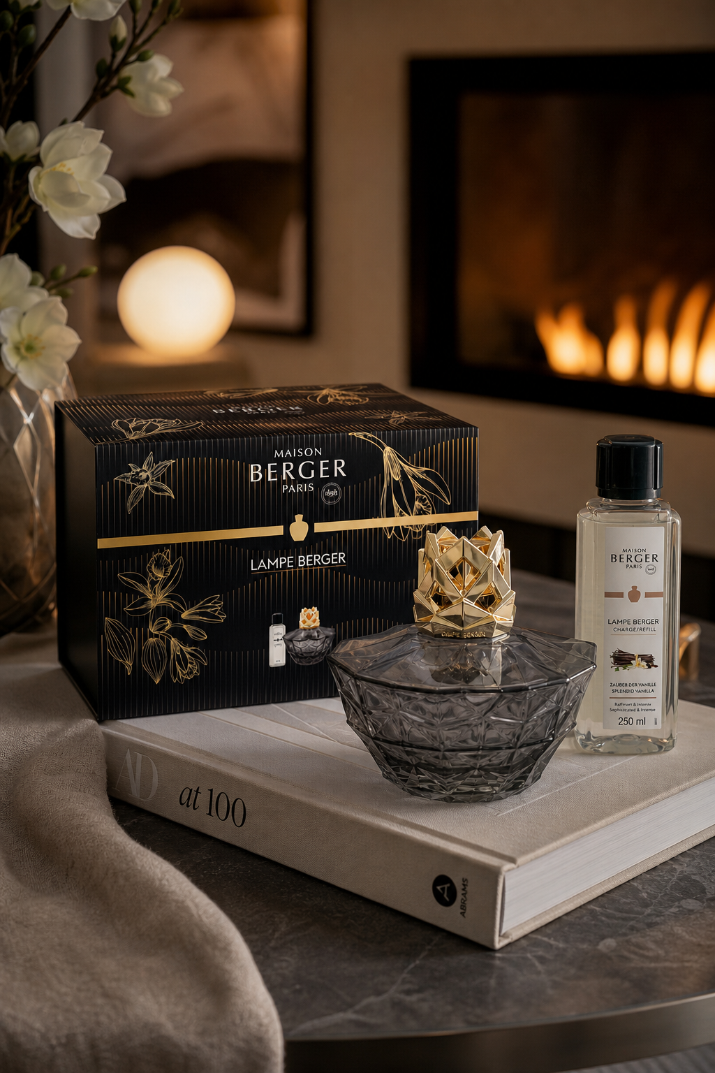 Kali Lampe Berger Set mit Verpackung und Nachfüllflasche auf einem Buch neben Kamin