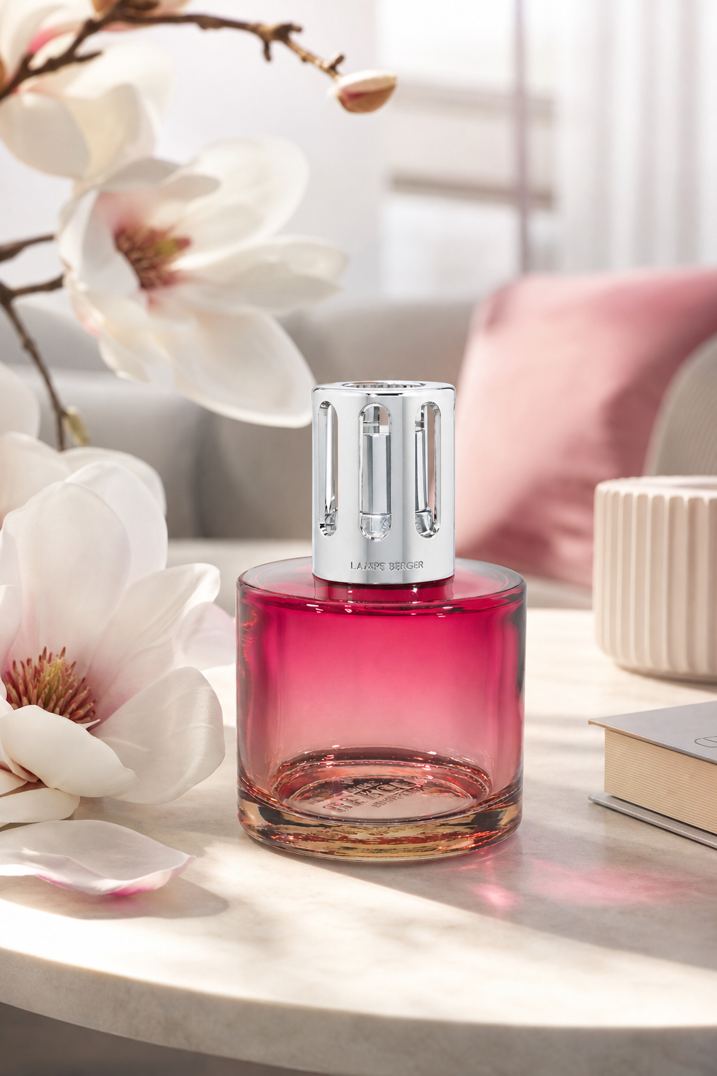Purpurfarbene Lampe Berger neben weißen Magnolienblüten auf einem Tisch