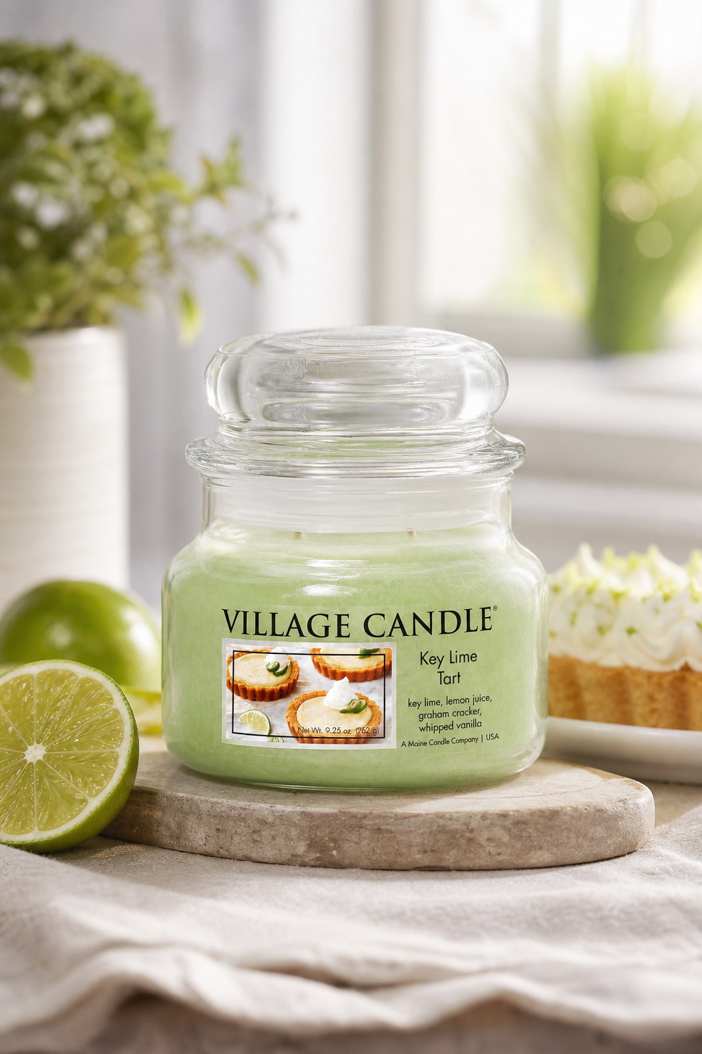 Village-Candle-Kerze mit Limetten und Kuchenmotiv auf Holzuntersetzer
