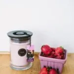 Rosa Kerze im Glas neben einer Schale mit Erdbeeren