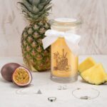 Jewel Candle L’Ananas neben Ananas, Passionsfrucht und mehreren Schmuckstücken