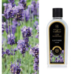 Flasche mit Lavendel-Lampenparfüm vor blühenden Lavendelpflanzen