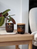Mehrere WoodWick ReNew Collection Kerzen auf Beistelltischen vor einem Sofa