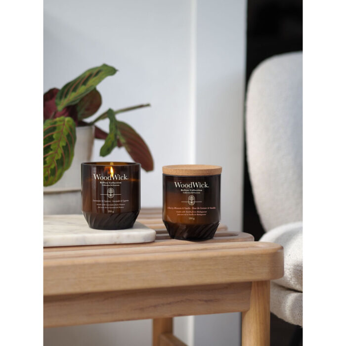 Mehrere WoodWick ReNew Collection Kerzen auf Beistelltischen vor einem Sofa