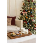 Zwei Yankee Candle Gläser neben Tee und Gebäck vor geschmücktem Weihnachtsbaum