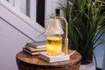 Leuchtender Kerzenwärmer mit Kerze auf einem runden Holztisch