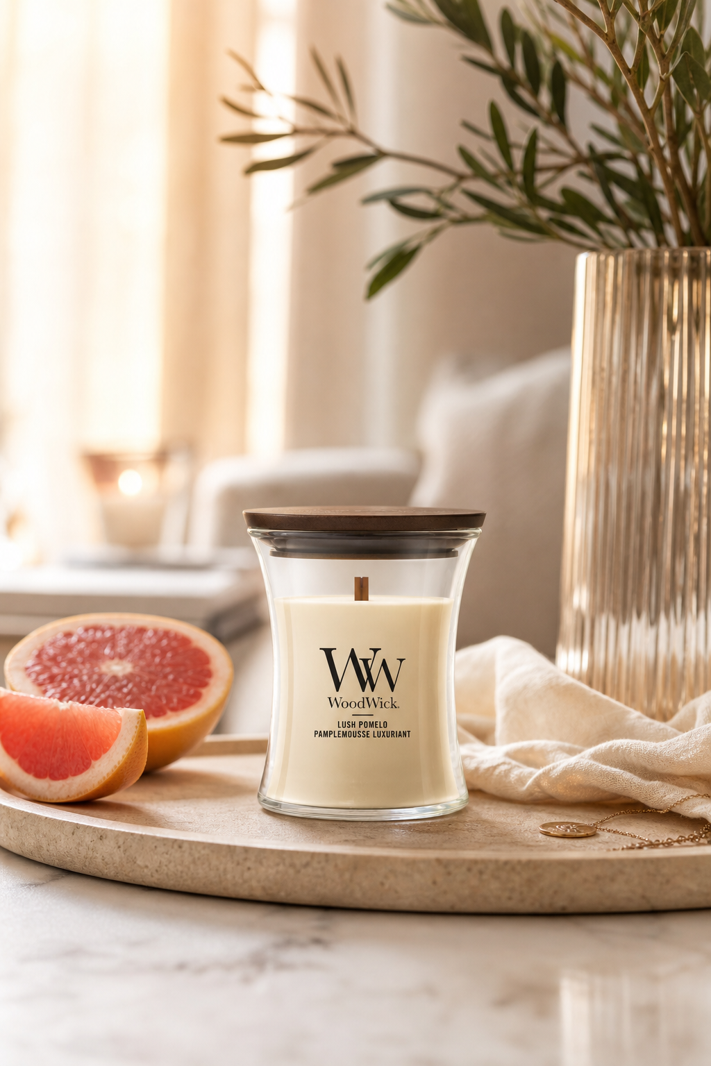 WoodWick Lush Pomelo Kerze auf Tablett neben aufgeschnittener Grapefruit