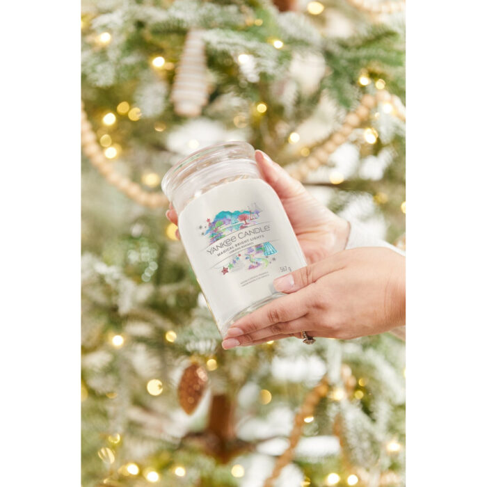 Brennende Magical Bright Lights Kerze auf Tisch vor Weihnachtsbaum
