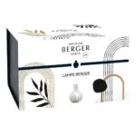 Weiße runde Lampe Berger steht auf einer hellen Tischplatte im Wohnraum