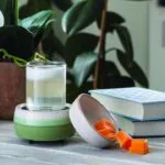 Grüne Duftlampe mit Trinkglas, Schale und orangefarbenen Wachswürfeln