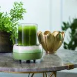 Grüne Duftlampe mit Glas eines grünen Getränks auf Tisch