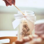Hand zündet die JewelCandle Kerze mit einem Holzstäbchen an