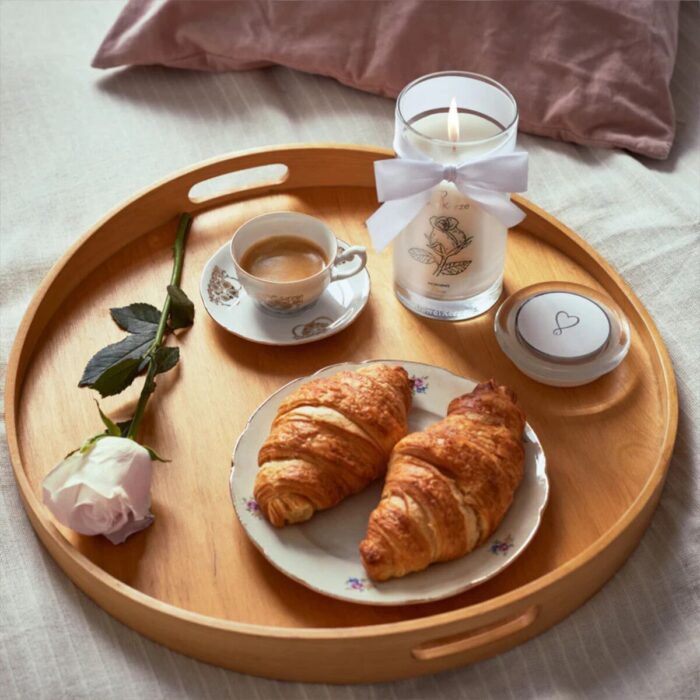 Brennende Morning Rose Kerze mit Rose, Kaffee und Croissants auf Holztablett