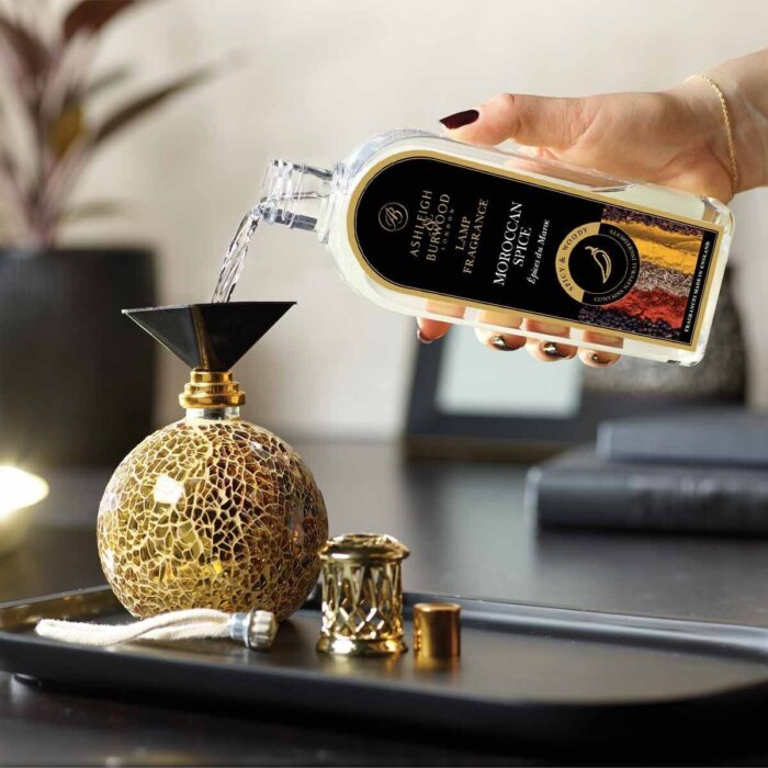 Moroccan Spice Lamp Fragrance wird aus einer Flasche in eine Duftlampe gegossen