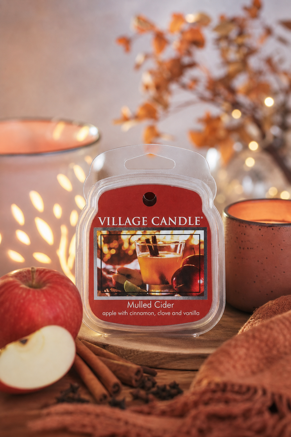 Village Candle Mulled Cider Verpackung zwischen Apfel, Zimtstangen und herbstlicher Dekoration
