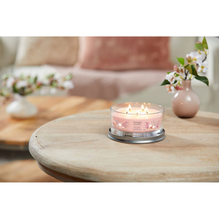 Brennende Pink Sands Kerze auf einem runden Holztisch