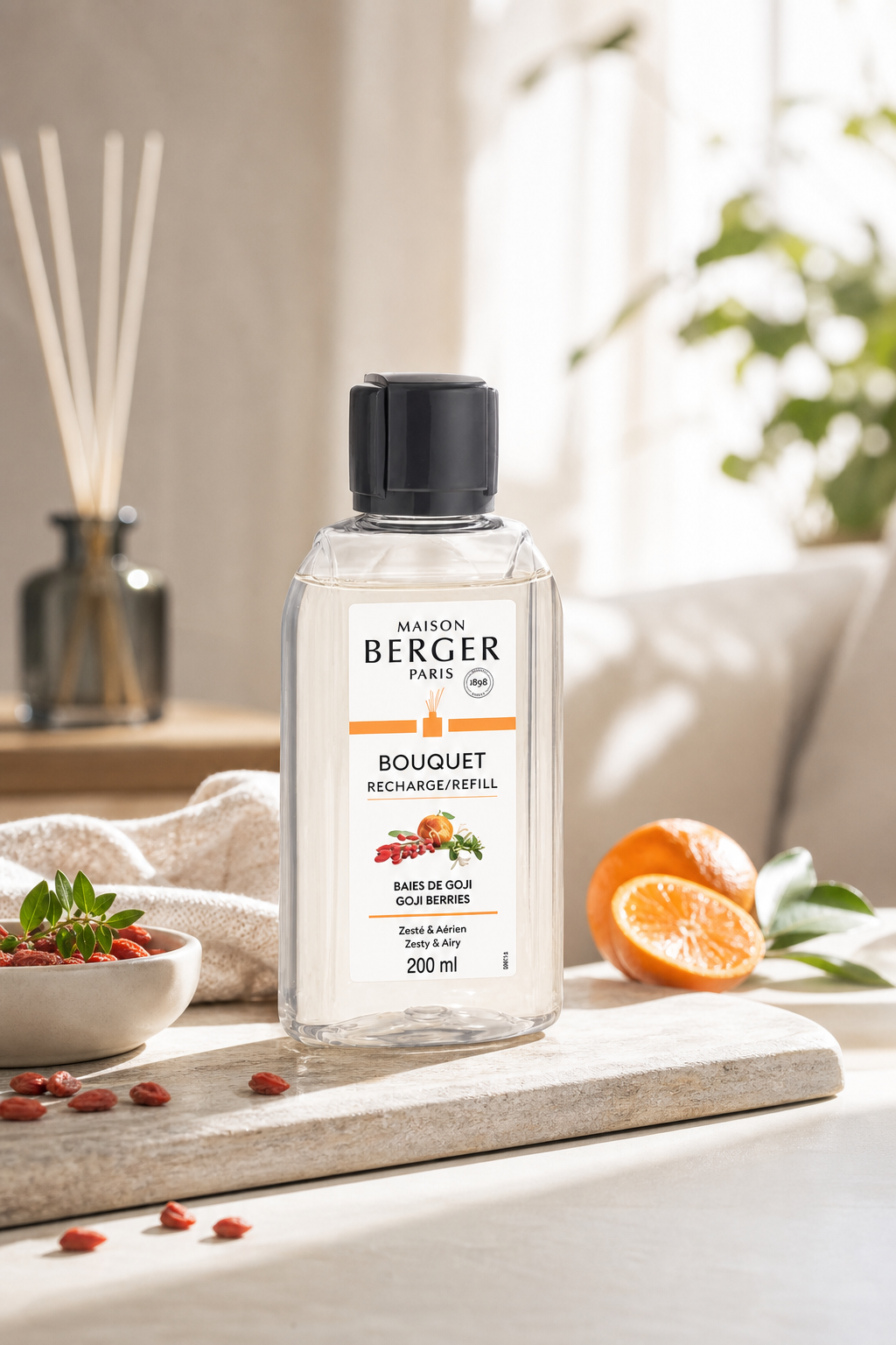 Maison Berger Goji-Beeren Nachfüller steht auf einem Tisch neben Duftstäbchen und Orangenscheiben