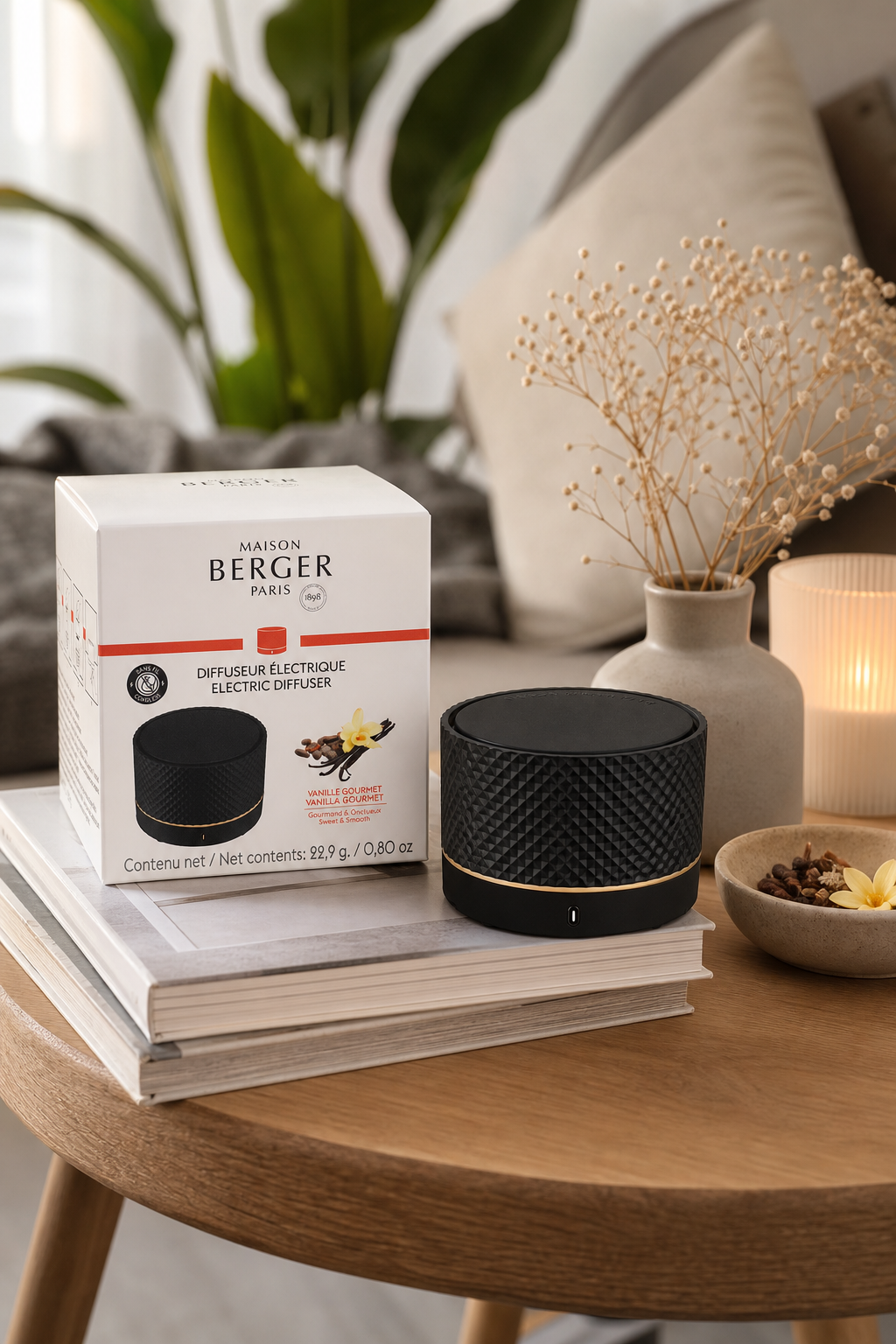 Schwarzer Duftdiffuser mit Verpackung auf Büchern neben Pflanze und Vase