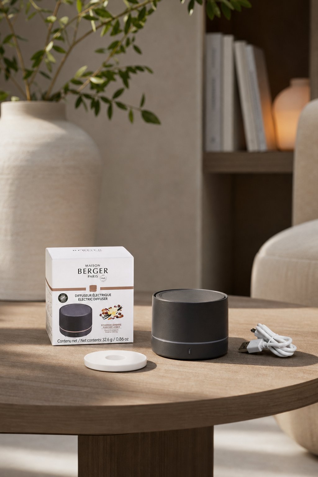 Grauer Duftdiffuser mit Verpackung und USB-Kabel auf einem Wohnzimmertisch