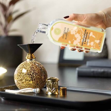 Hand gießt Orange Blossom & Mandarin Lamp Fragrance in eine dekorative Duftlampe