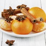 Brennende Orange-Cinnamon-Kerze mit geöffnetem Glasdeckel auf einem Tisch