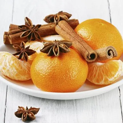 Brennende Orange-Cinnamon-Kerze mit geöffnetem Glasdeckel auf einem Tisch