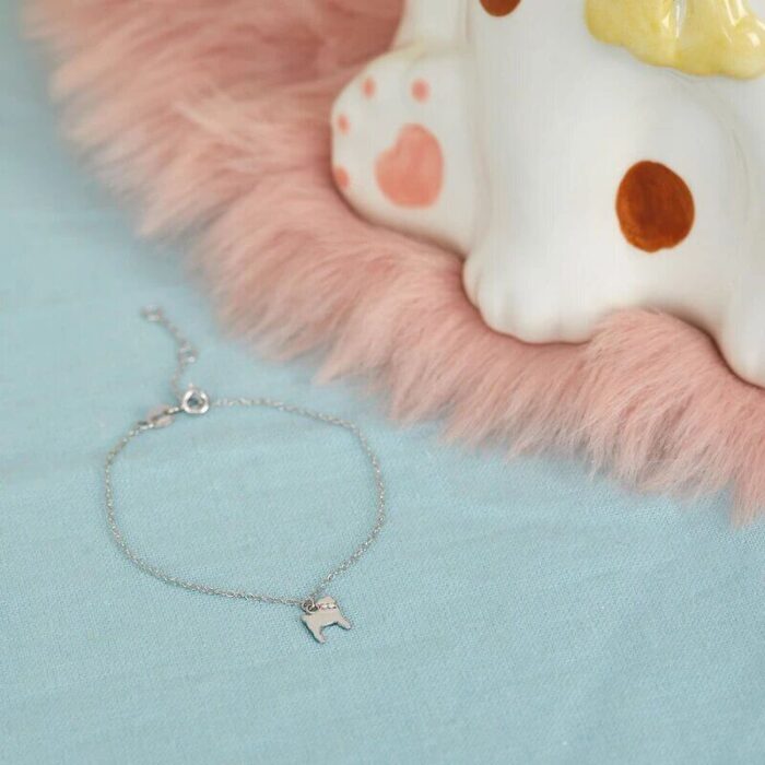 Silberfarbenes Armband mit Hundeanhänger neben der Hundfigur