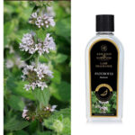 Patchouli-Duftlampenölflasche neben blühender Patchouli-Pflanze