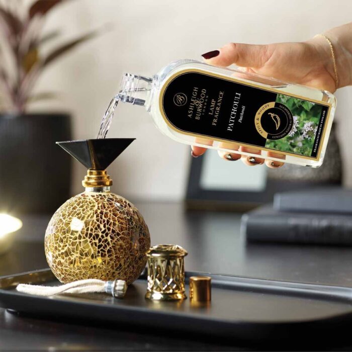 Flasche gießt Patchouli-Lamp-Fragrance in eine Duftlampe