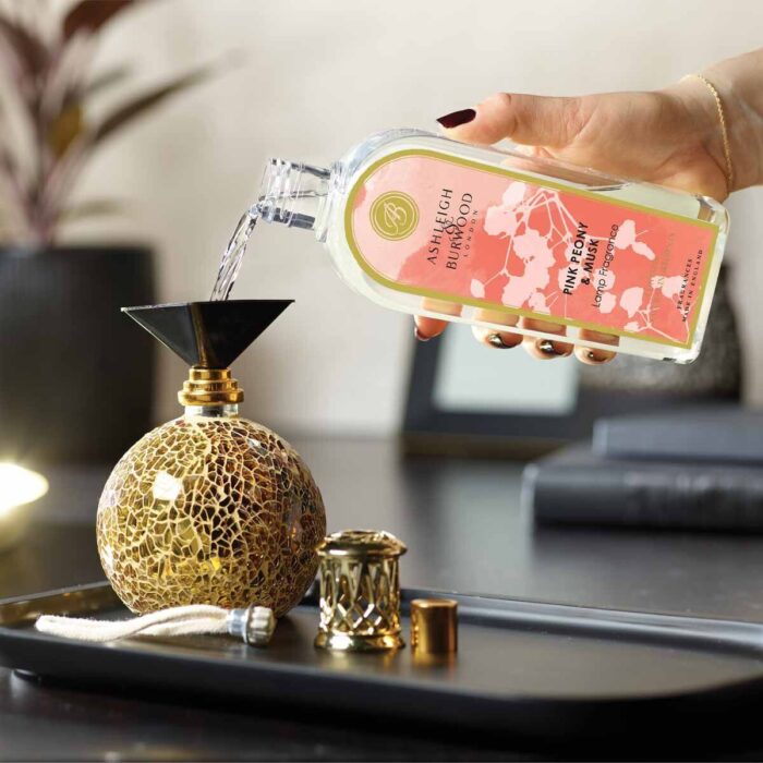 Person gießt Pink Peony & Musk Lamp Fragrance in eine Duftlampe