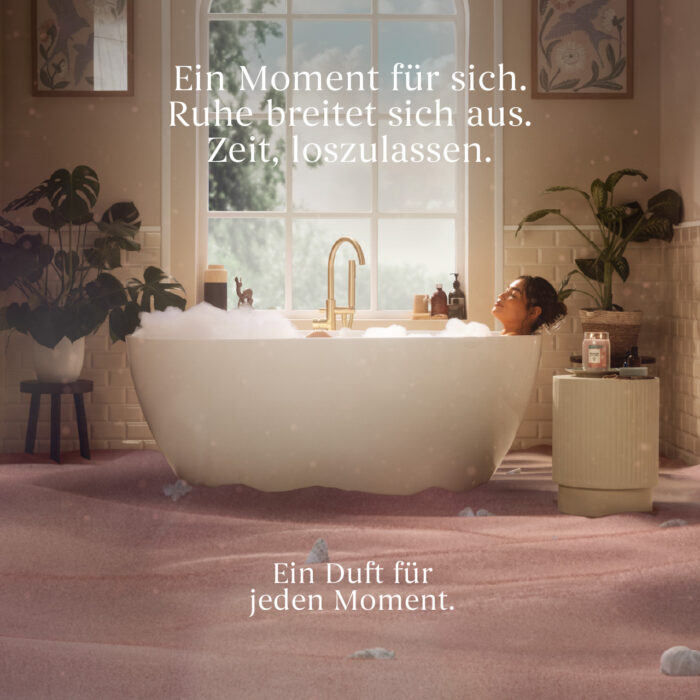Person entspannt in einer Badewanne neben einem Duftprodukt