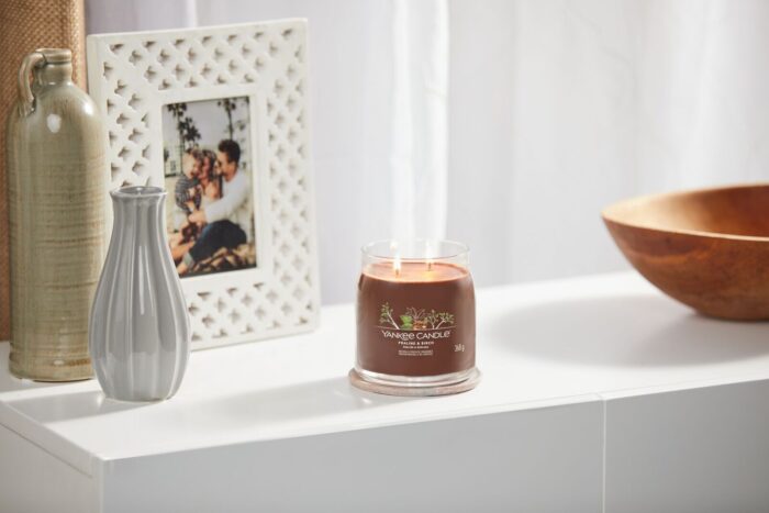 Brennende Yankee Candle Praline & Birch Kerze neben Vasen und Bilderrahmen