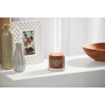 Brennende Yankee Candle Praline & Birch Kerze neben Vasen und Bilderrahmen