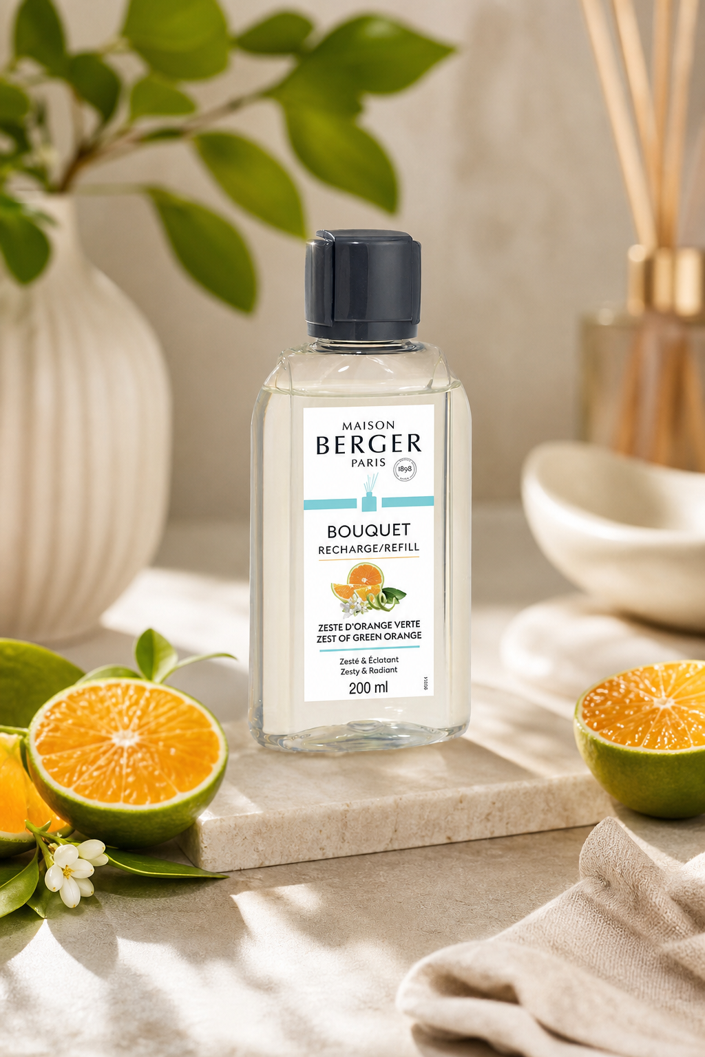 Maison Berger Nachfüllflasche neben Orangen und Duftstäbchen