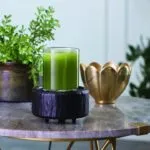 Schwarze Duftlampe mit grünem Glasbehälter auf einem Tisch