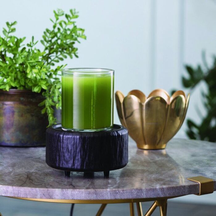 Schwarze Duftlampe mit grünem Glasbehälter auf einem Tisch
