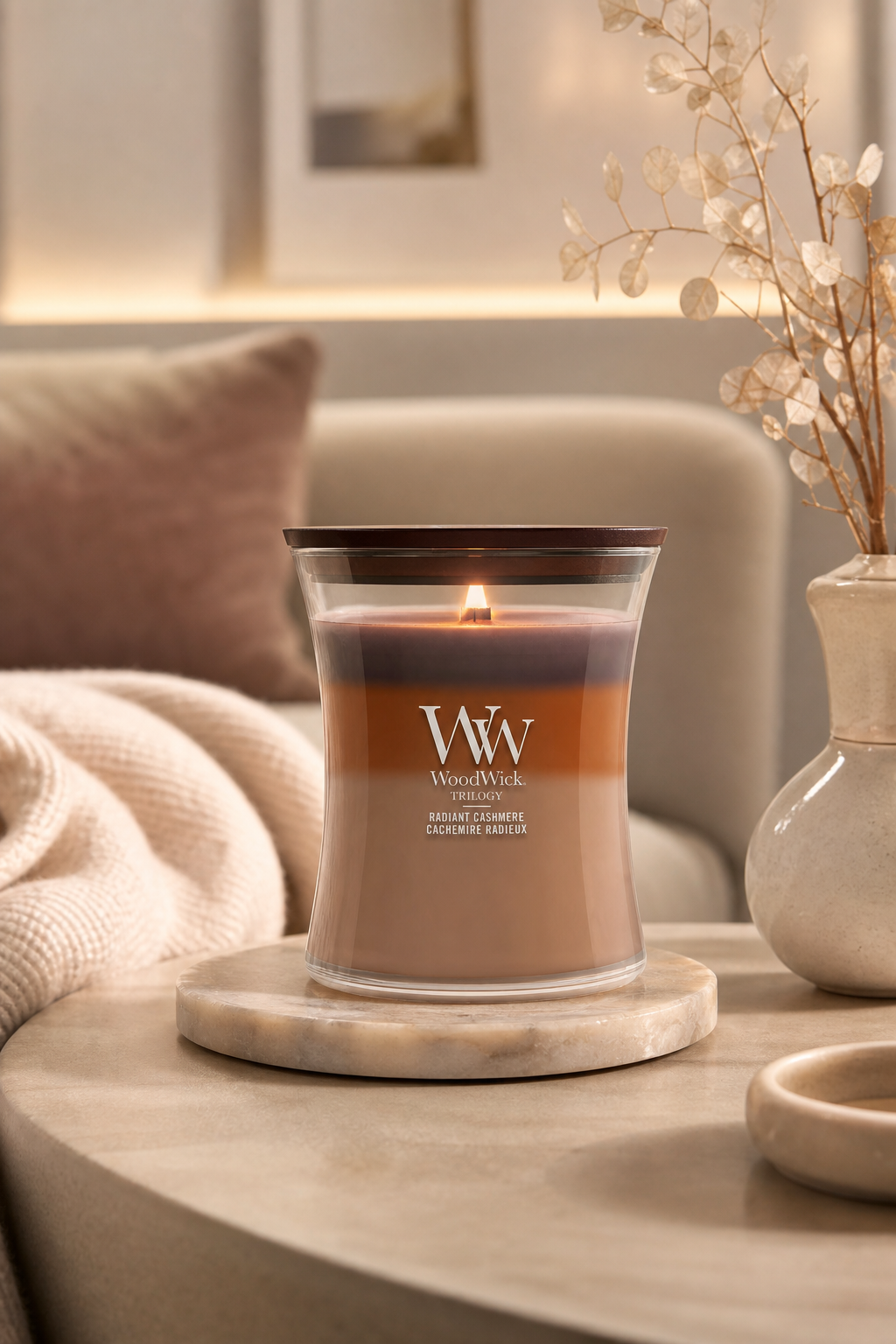 Brennende WoodWick Trilogy Radiant Cashmere Kerze auf einem Wohnzimmertisch
