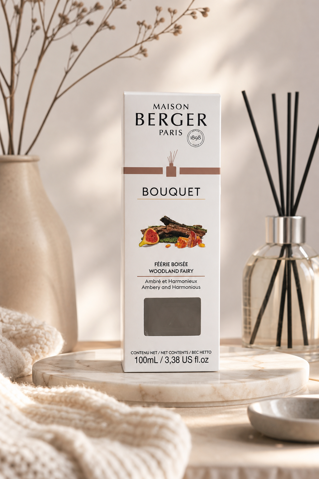 Maison Berger Raumduft-Verpackung neben einem Diffuser mit schwarzen Duftstäbchen