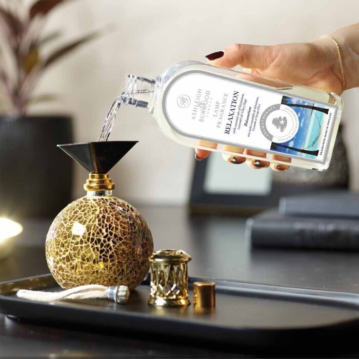 Hand gießt Relaxation Lamp Fragrance aus Flasche in eine Duftlampe