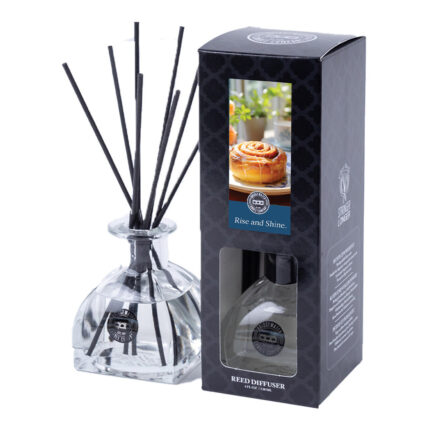 Glasflakon mit schwarzen Duftstäbchen neben der Rise-and-Shine-Verpackung