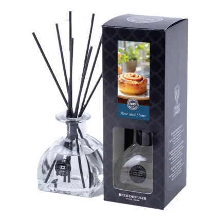 Glasflakon mit schwarzen Duftstäbchen neben der Rise-and-Shine-Verpackung