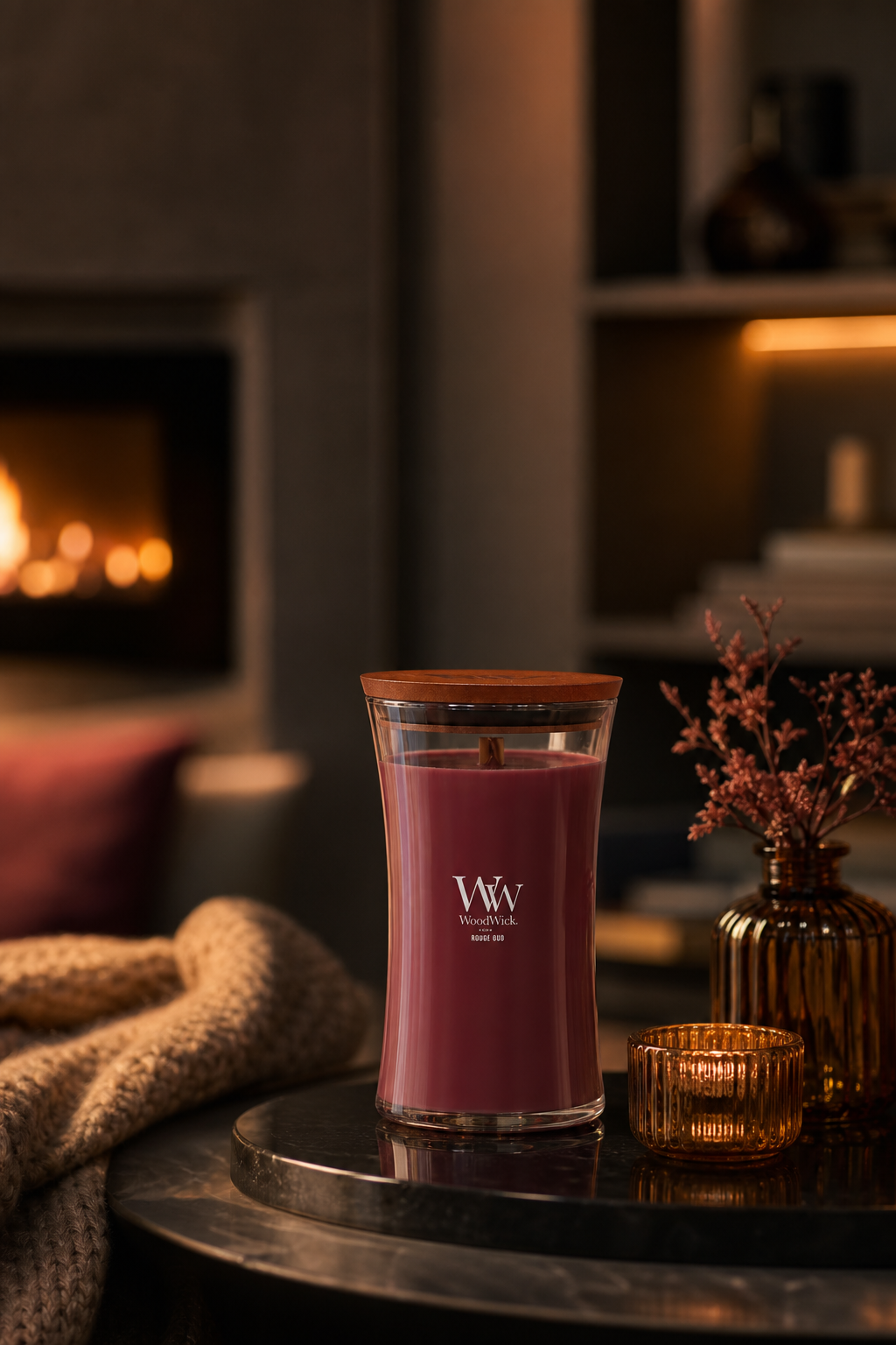 WoodWick Rouge Oud Kerze auf einem runden Tisch vor Kamin