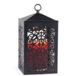 Schwarze Laterne mit warm leuchtendem roten Licht hinter Ornamentmuster