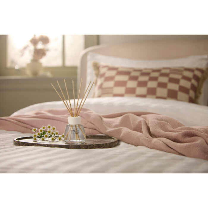 Reed Diffuser mit Duftstäbchen auf einem Tablett vor einem Bett