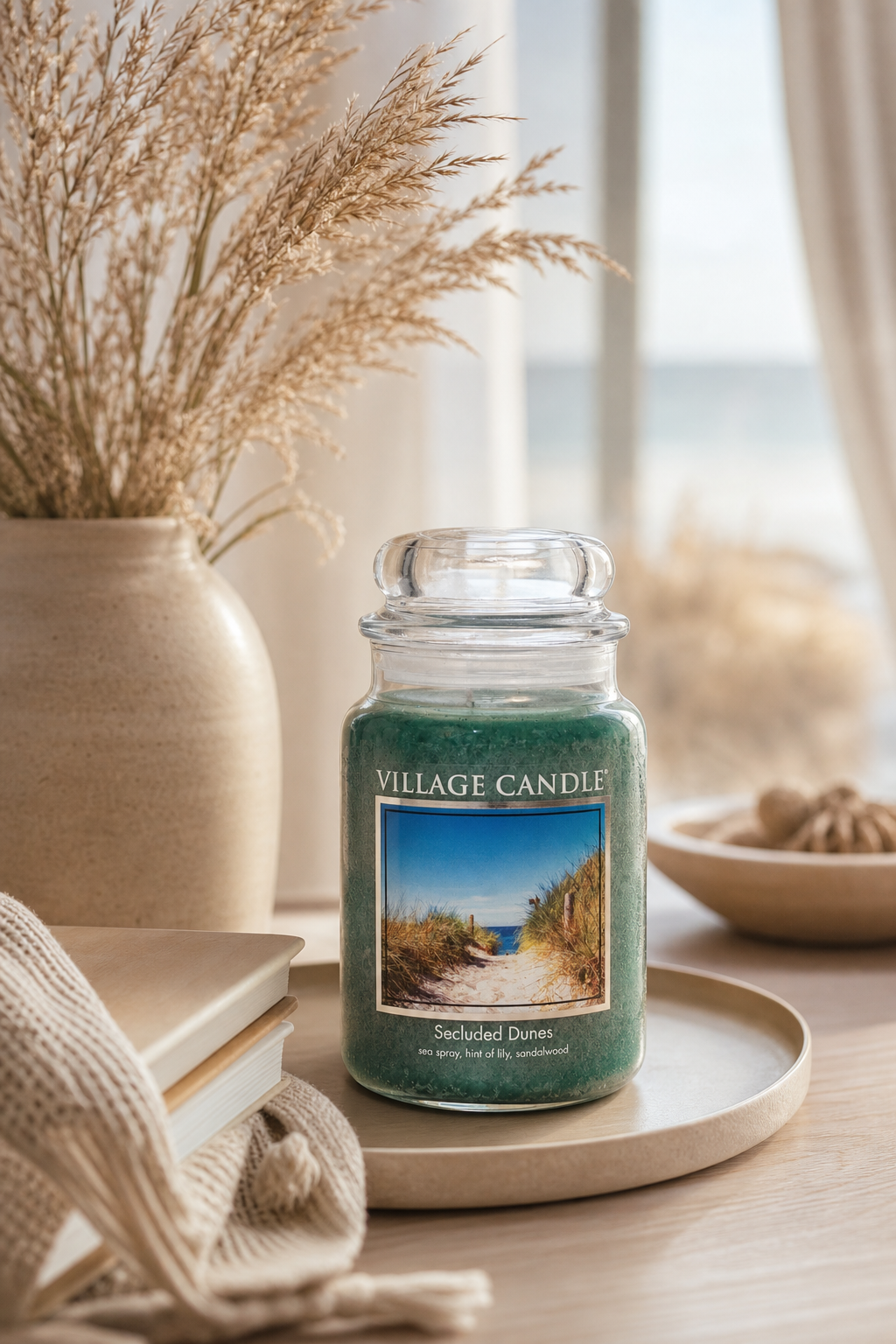Village Candle Secluded Dunes auf Tablett neben Vase und Büchern