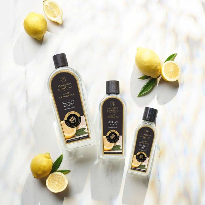 Drei Sicilian Lemon Lamp Fragrance Flaschen mit Zitronen auf hellem Untergrund