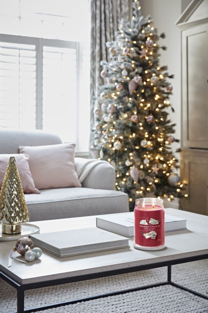 Brennende Letters to Santa Kerze steht auf Couchtisch vor Weihnachtsbaum
