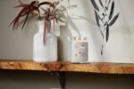 Yankee Candle Duftkerze mit zwei Flammen neben Vase und Wandbild